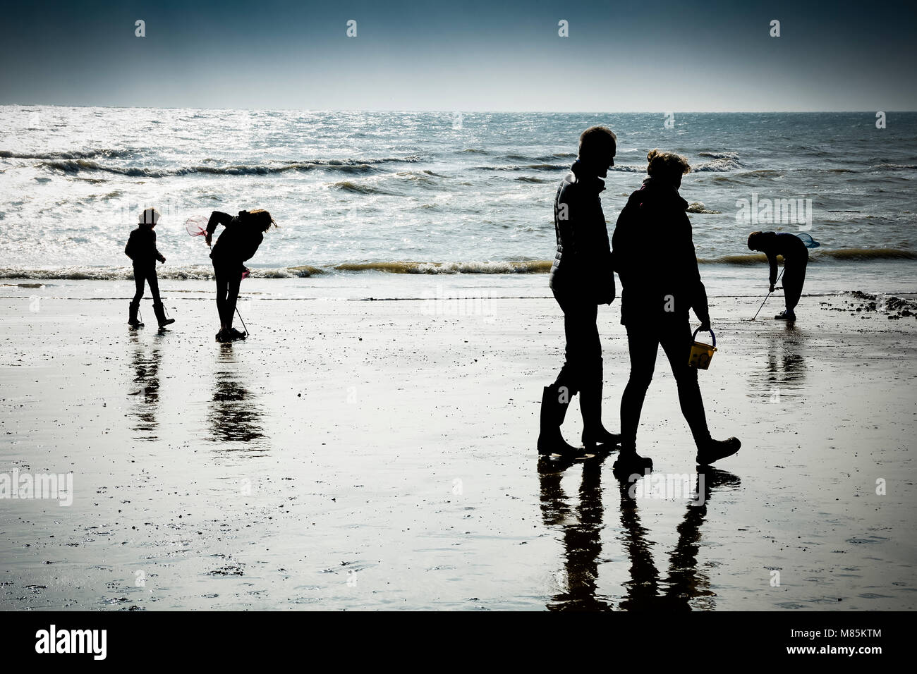 Famiglia godendo il mare a piedi e scavando sulla spiaggia Foto Stock