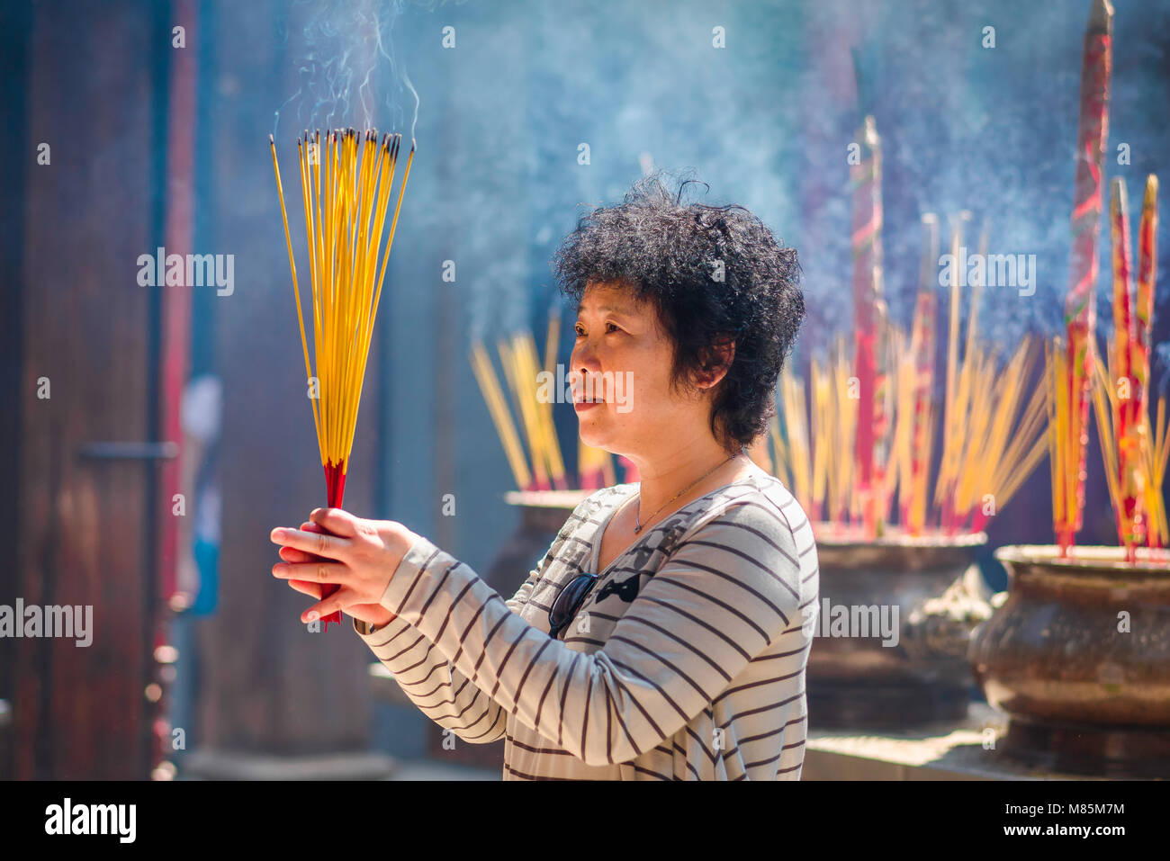 Sud-est asiatico di persone, una donna rende culto al Tempio Thien Hau nell'area di Cholon di Ho Ci Minh City (Saigon) Vietnam. Foto Stock