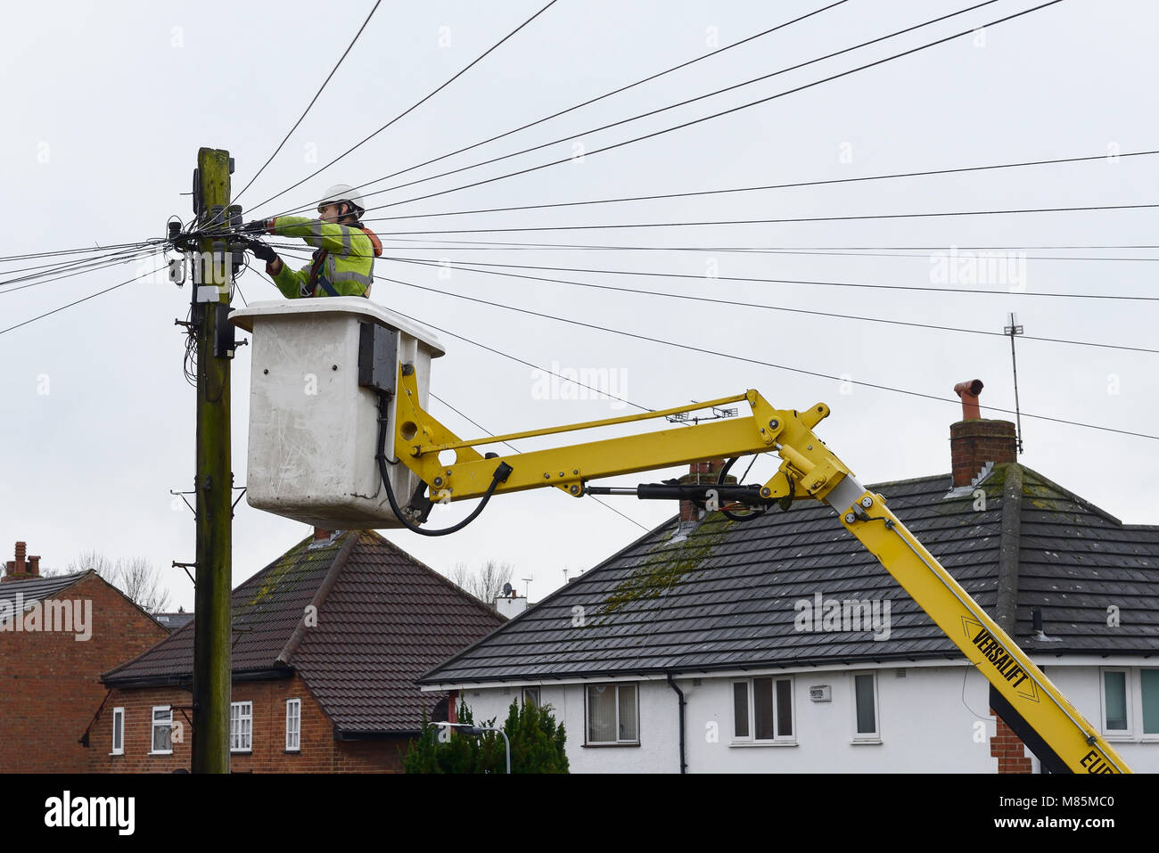 Un BT Openreach ingegnere di lavoro sui cavi telefonici da un cherry picker Foto Stock