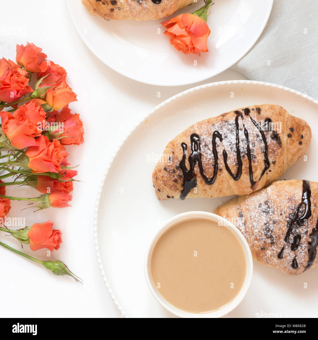 Pane appena sfornato croissant al cioccolato e la tazza di caffè sul tavolo bianco. Vista dall'alto. A molla femmina prima colazione concetto. Copia dello spazio. Foto Stock