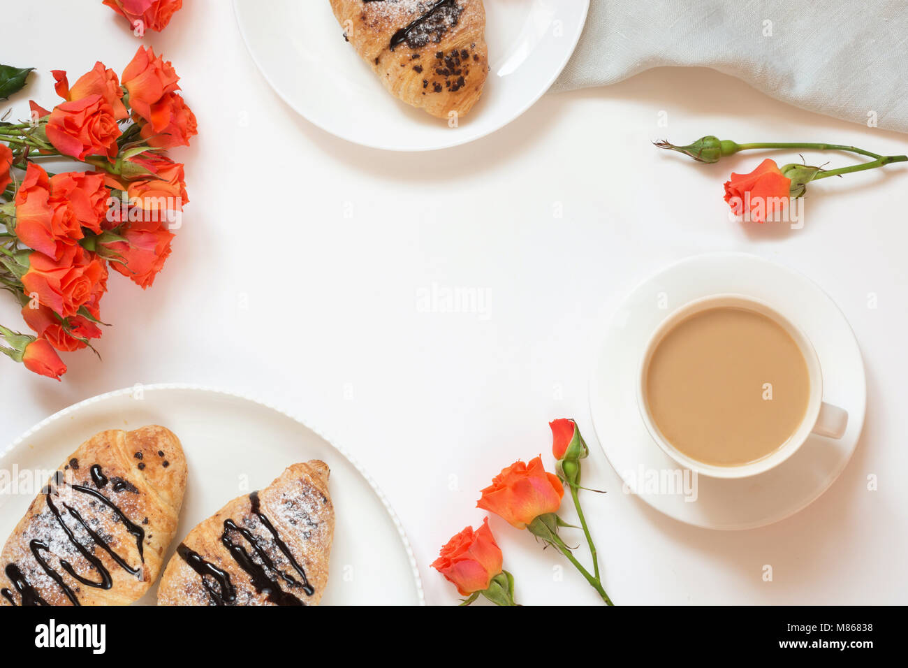 Pane appena sfornato croissant al cioccolato e la tazza di caffè sul tavolo bianco. Vista dall'alto. A molla femmina prima colazione concetto. Copia dello spazio. Foto Stock
