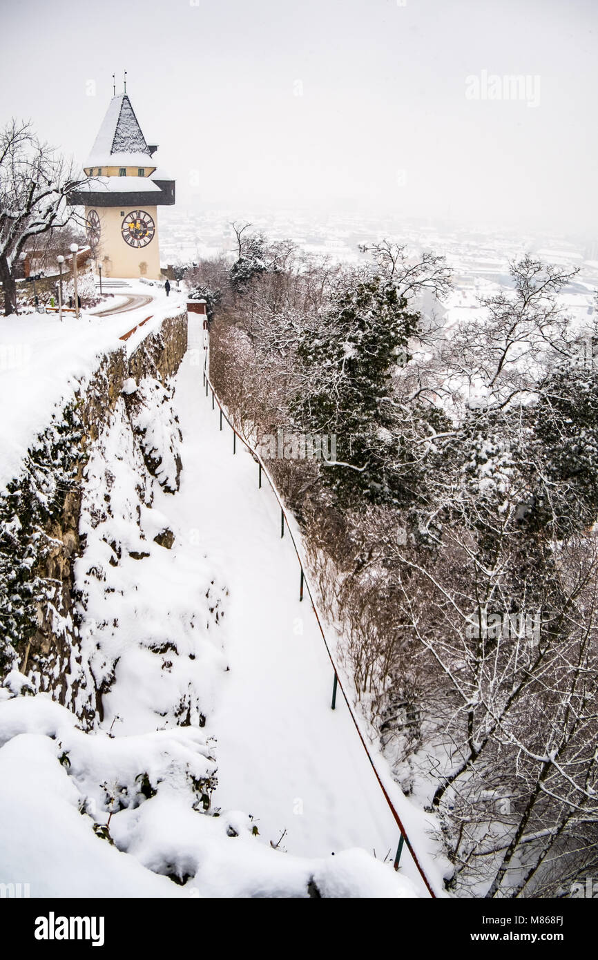 Percorso al coperto di neve Uhrturm clocktower punto di riferimento della città di Graz sulla collina Schlossberg in inverno Foto Stock