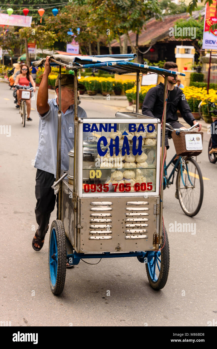 Un uomo spinge un camion vendere Banh Bao, un pane cotto a vapore snack, ad Hoi An, Vietnam Foto Stock