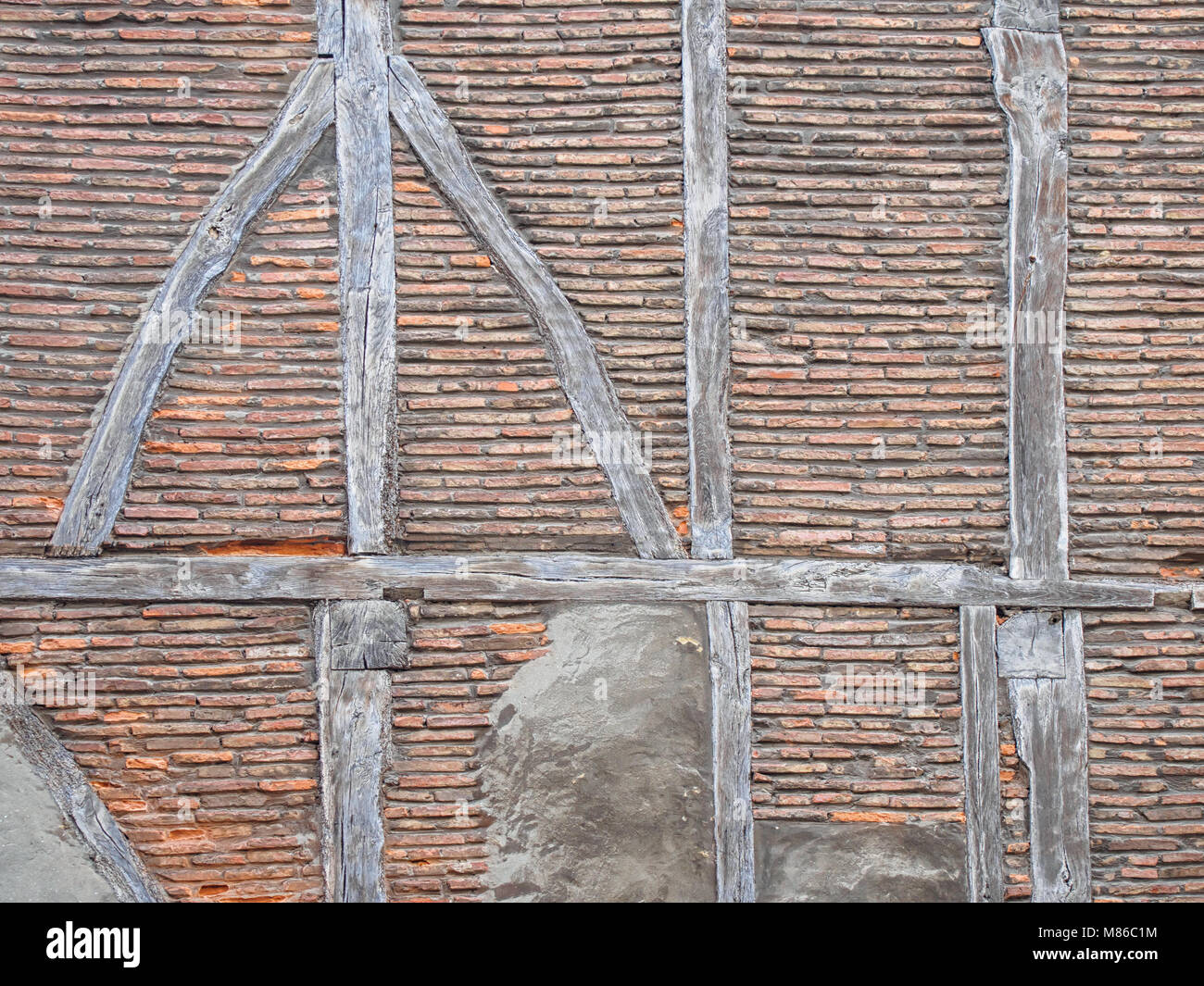 Antica incorniciatura di legno (post-e-beam) muro di mattoni in background Foto Stock