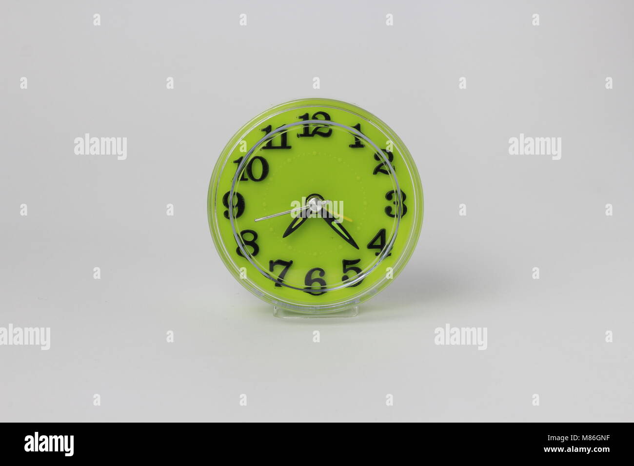 Un verde orologio sveglia con uno sfondo bianco posizionato nel centro Foto Stock