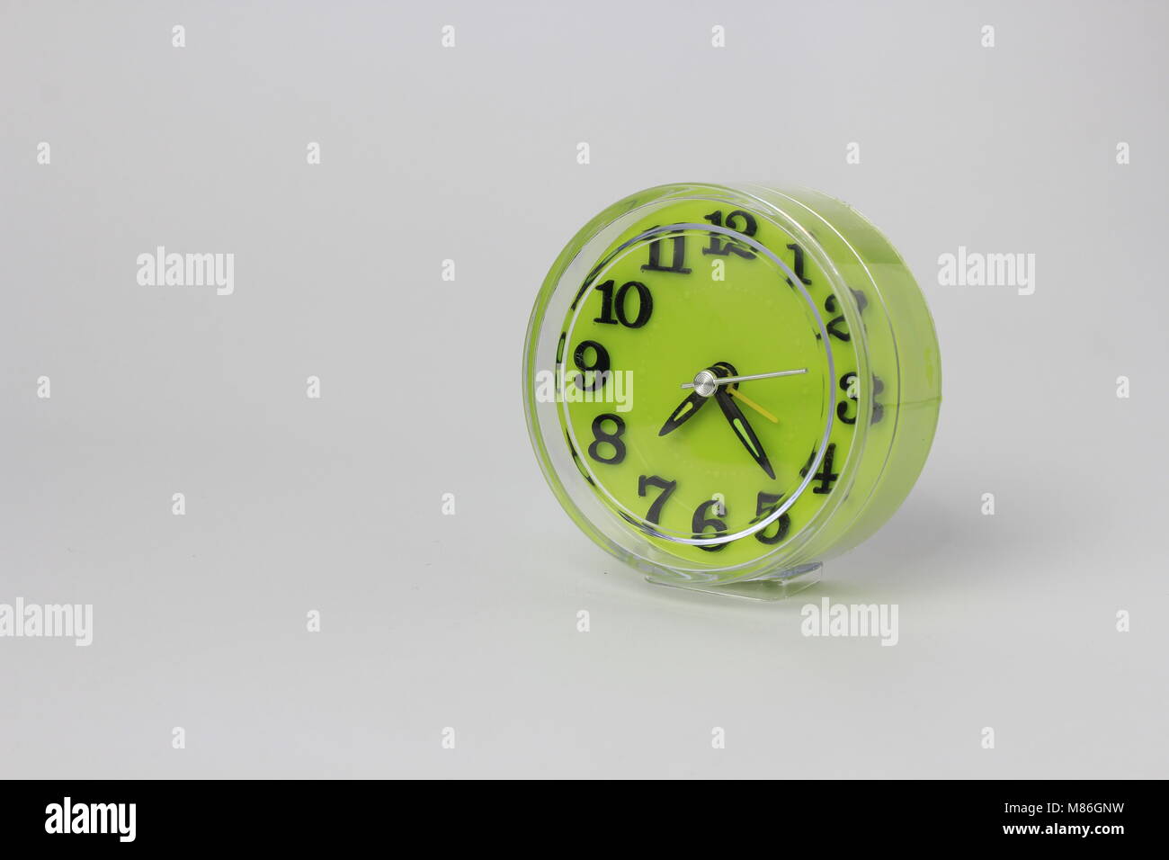 Un verde orologio sveglia con uno sfondo bianco posizionato a destra Foto Stock