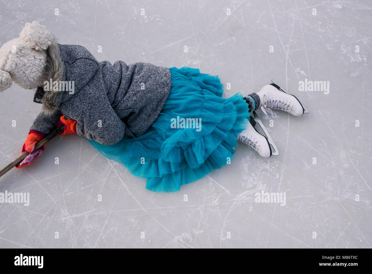 Ragazza distesa su un lago ghiacciato in possesso di una mazza da hockey Foto Stock