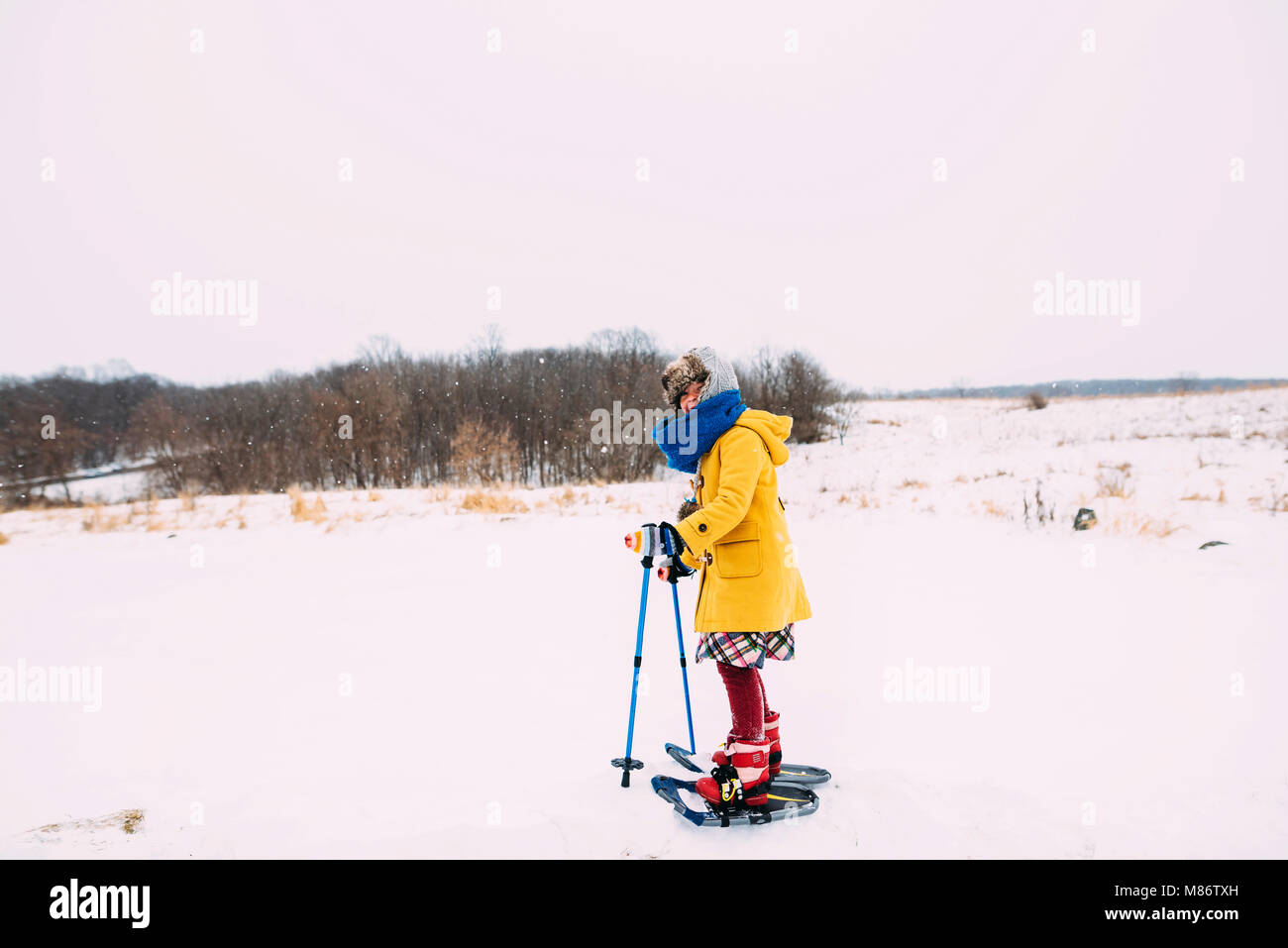 Ragazza con le racchette da neve in zone rurali paesaggio invernale Foto Stock