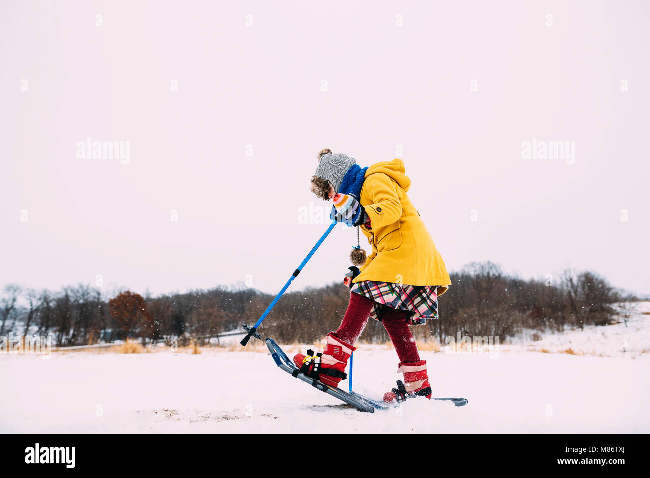 Ragazza con le racchette da neve nel paesaggio rurale Foto Stock