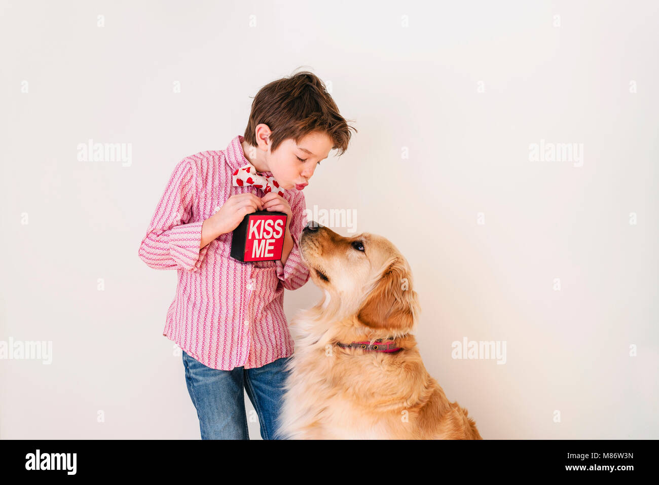 Ragazzo soffia un bacio al suo golden retriever cane Foto Stock