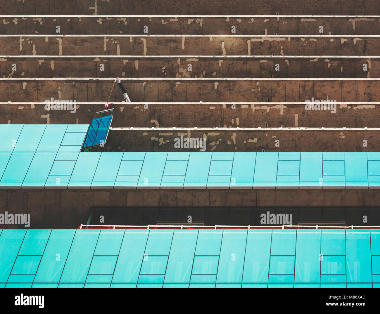 Una gru posizionando un bicchiere in un cantiere di un grattacielo moderno Foto Stock