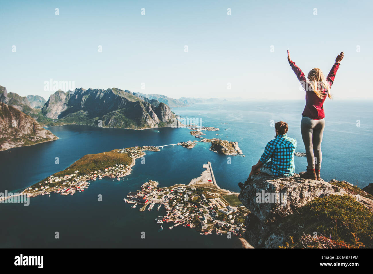 Giovane famiglia che viaggiano insieme sulla scogliera edge in Norvegia l uomo e la donna il concetto di stile di vita le vacanze estive all'aperto vista aerea Isole Lofoten Reinebri Foto Stock