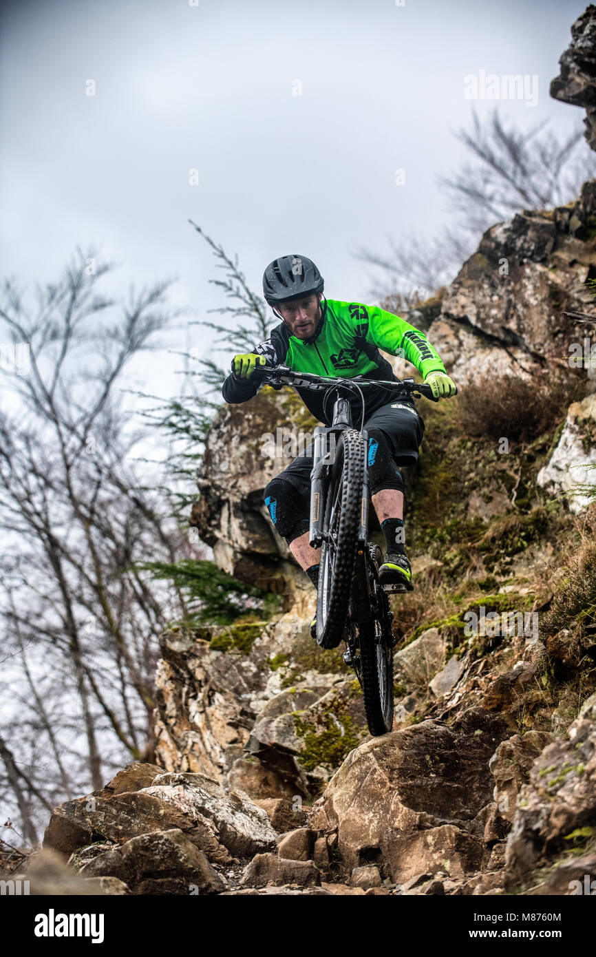 Un mountain biker cavalca un sentiero roccioso a Coed-y-Brenin in Snowdonia, il Galles del Nord. Foto Stock