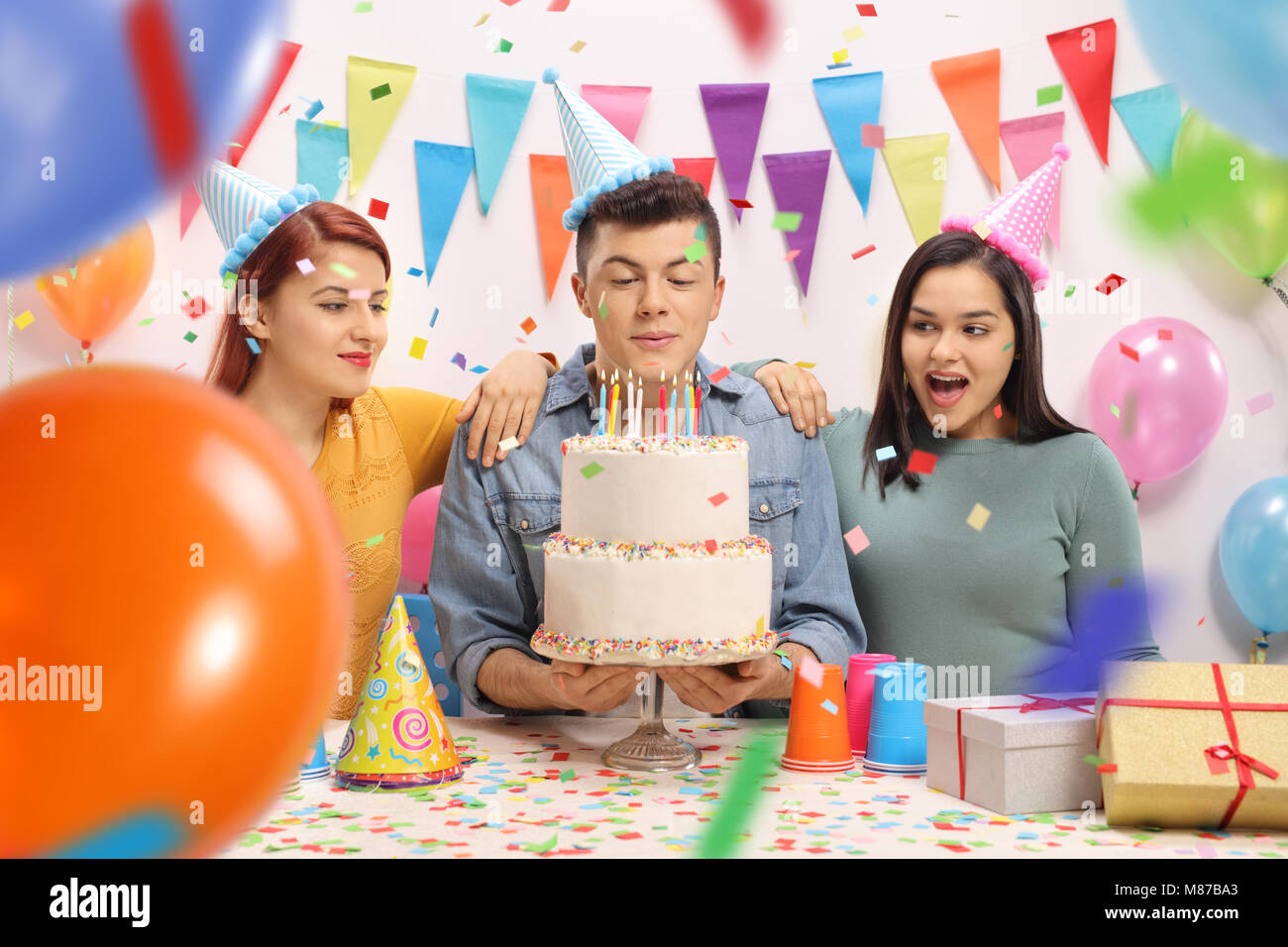 Gli adolescenti con party cappelli e una torta per festeggiare un compleanno Foto Stock