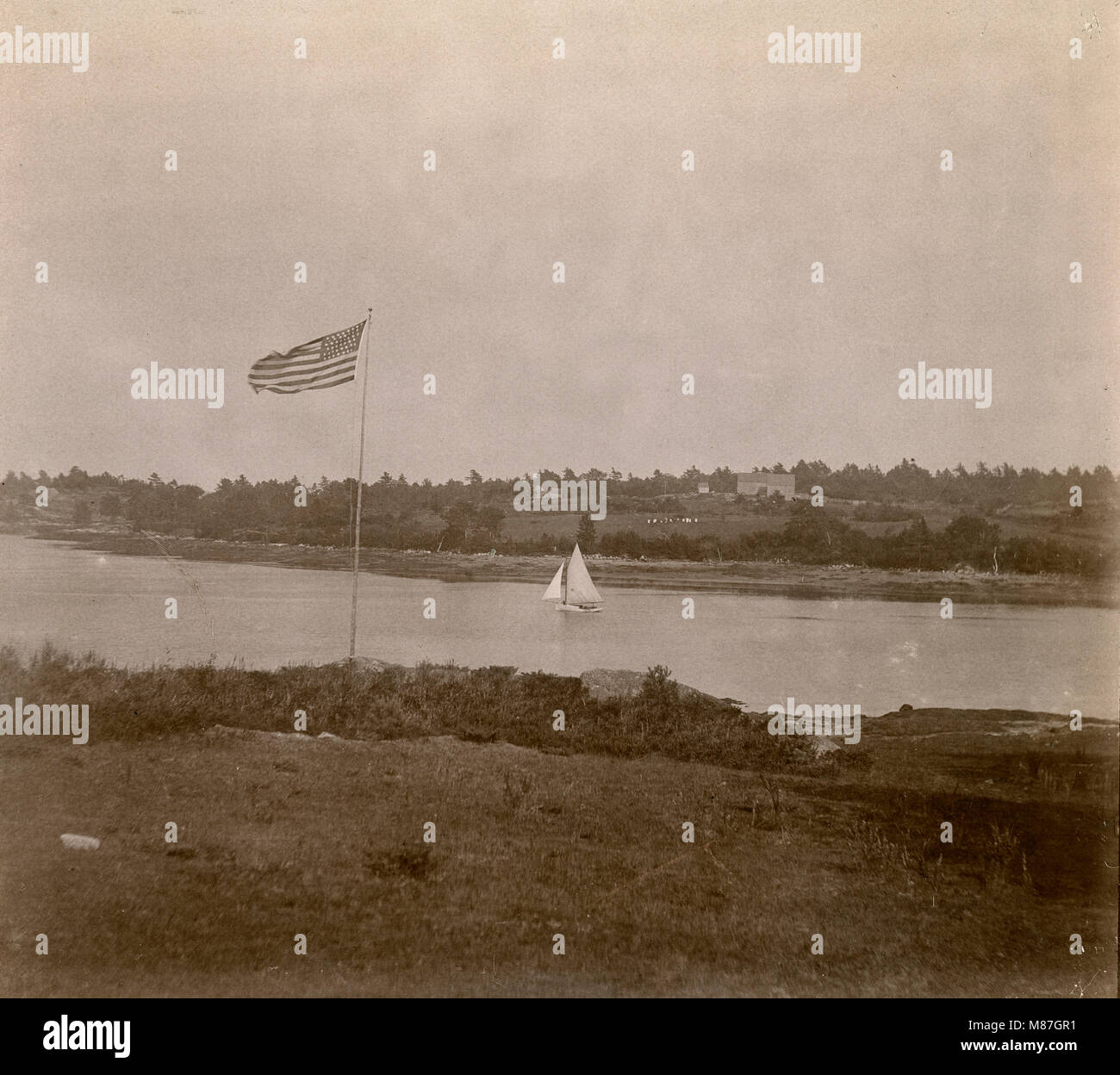 Antique circa 1905 fotografia, 45-stella bandiera e la barca a vela nel fiume Sasanoa. La posizione è in o vicino a Riggsville (ora Robinhood), Maine in Sagadahoc County, Stati Uniti d'America. Foto Stock