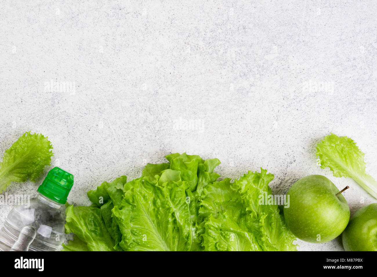 Mangiare sano. Mela verde, insalata di lattuga a foglia, bottiglia d'acqua su sfondo bianco. Dieta dimagrante, e pesare il concetto di perdita. Copiare lo spazio e la vista superiore Foto Stock