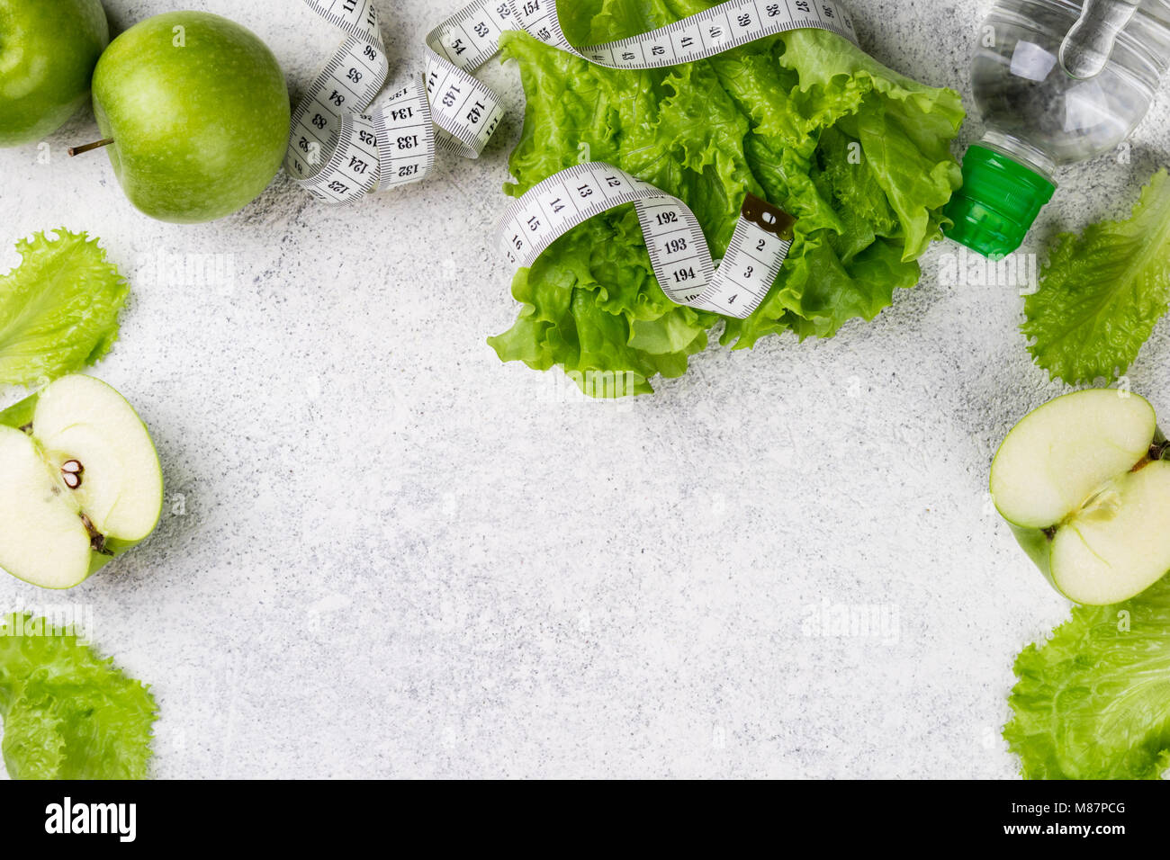 Mangiare sano. Mela verde, insalata di lattuga, acqua in bottiglia, nastro di misurazione. Dieta dimagrante, e pesare il concetto di perdita. Copiare lo spazio e la vista superiore Foto Stock