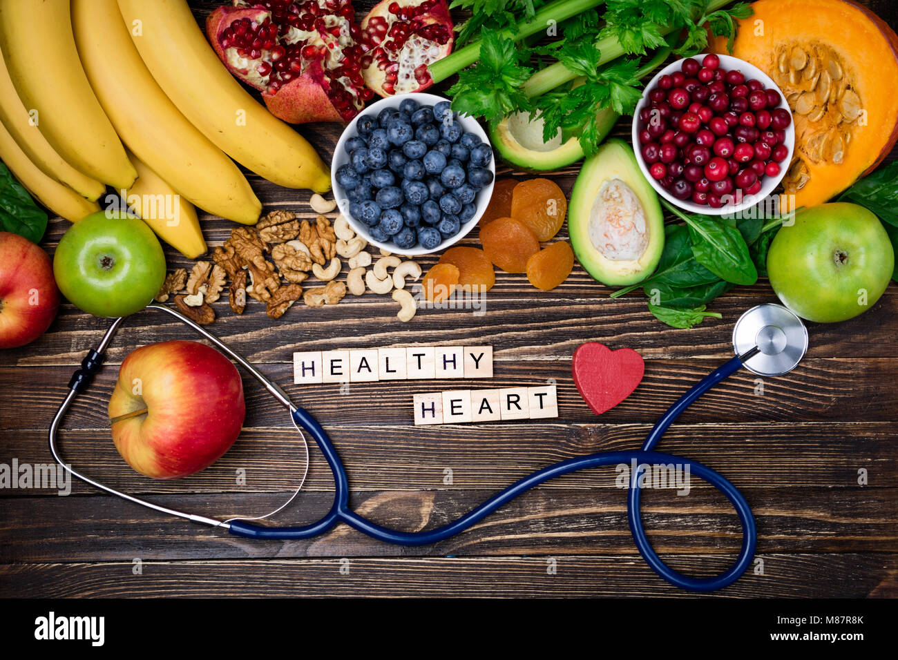 Sullo sfondo di un alimento sano per il cuore. Cuore sano concetto. Cibo sano, dieta e vita. La frutta e la verdura fresca, frutti di bosco e i dadi Foto Stock