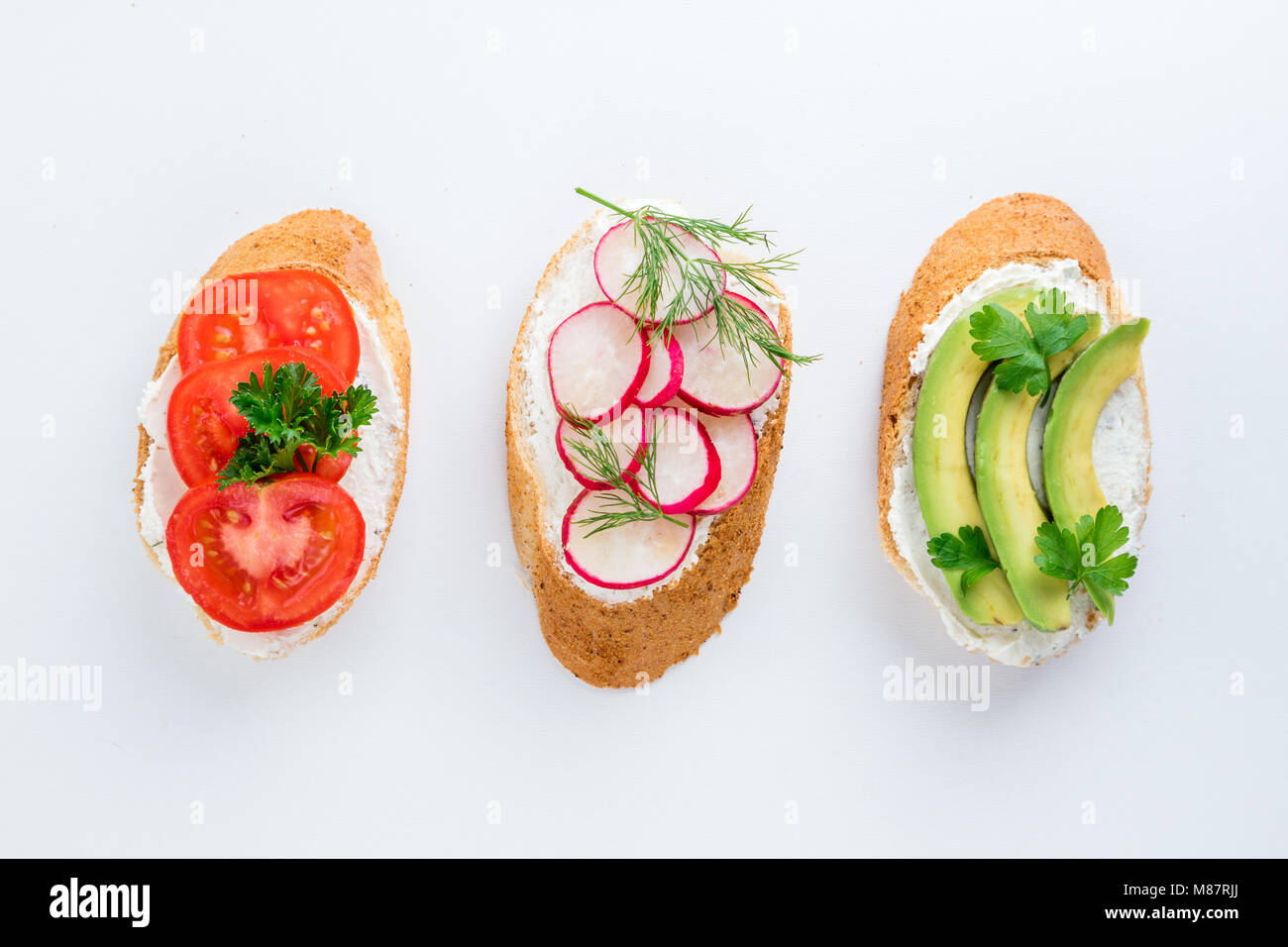 Mini sandwich con crema di formaggio, verdure e avocado. Varietà di panini su sfondo bianco, vista dall'alto. Lay piatto. Spazio di copia Foto Stock