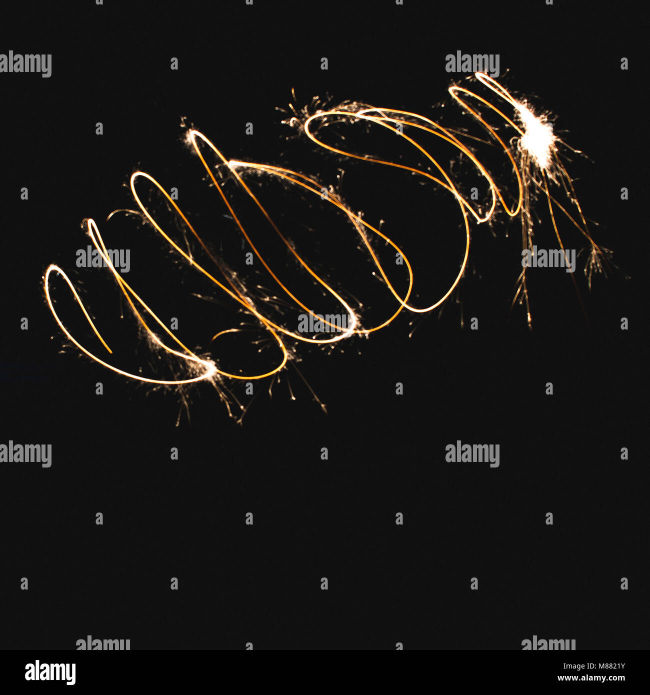 Scarabocchio forme realizzate con un sparkler in un giardino con una lunga esposizione. Foto Stock