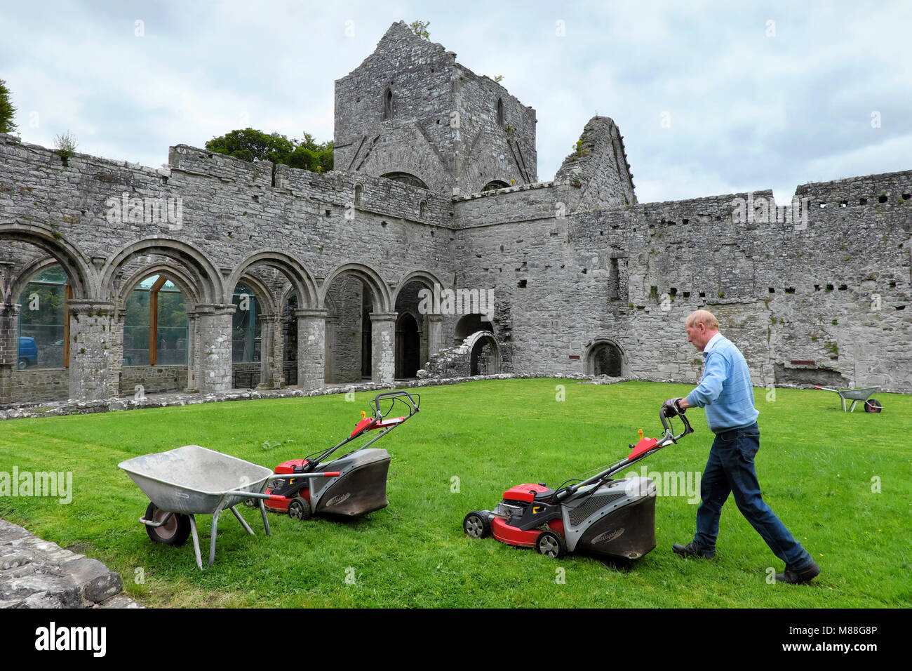 Un uomo anziano bidello / / custode mows il prato, Abbazia di Boyle, Sycamore Crescent, Boyle, nella contea di Roscommon, Irlanda Foto Stock