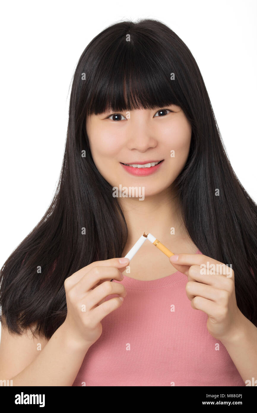 Bella donna asiatica sorridere mentre la rottura di una sigaretta per smettere di fumare isolato su uno sfondo bianco Foto Stock