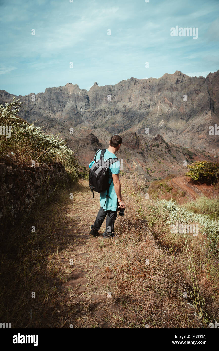 Escursionista ammirando brullo paesaggio naturale di fronte robusta gamma di montagna. Itinerari di trekking in una giornata di sole da corda a Coculli Santo Antao Capo Verde Foto Stock