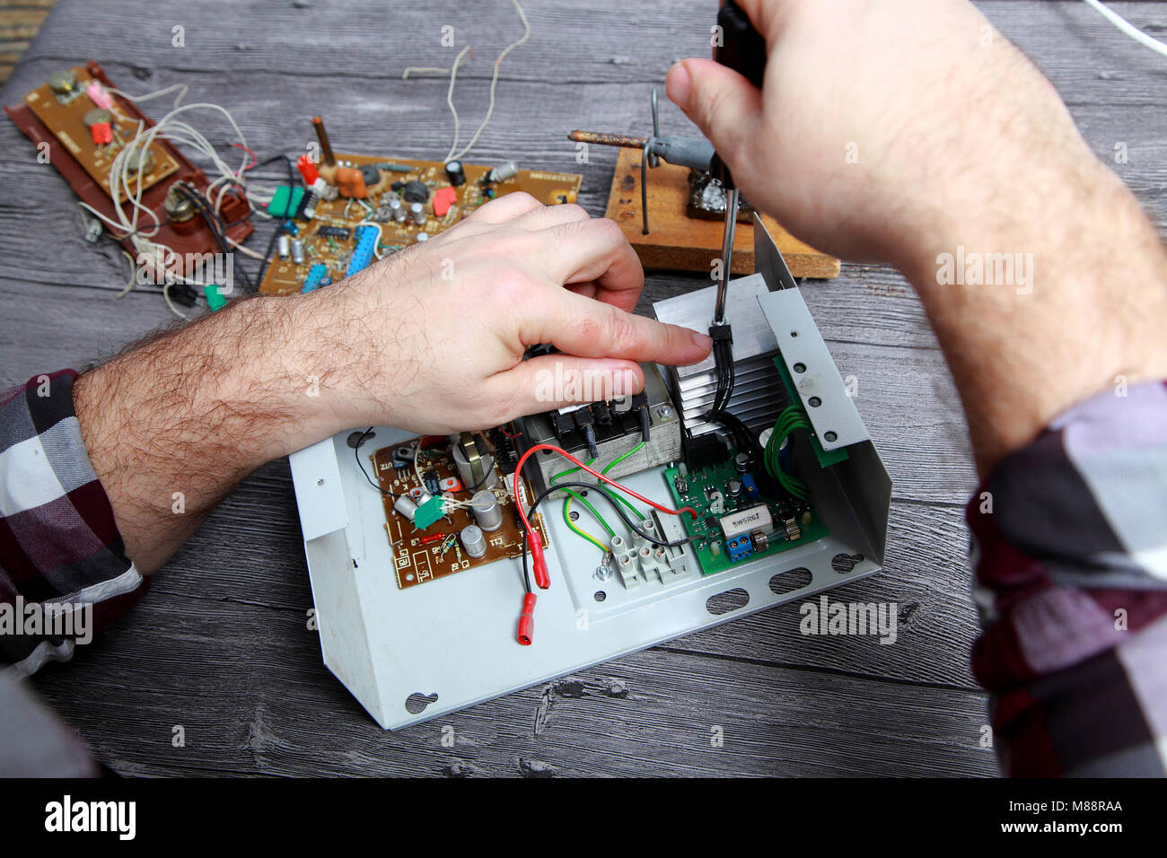 Il lavoro del maestro per la riparazione di apparecchiature elettroniche, si svita il filo di messa a terra Foto Stock