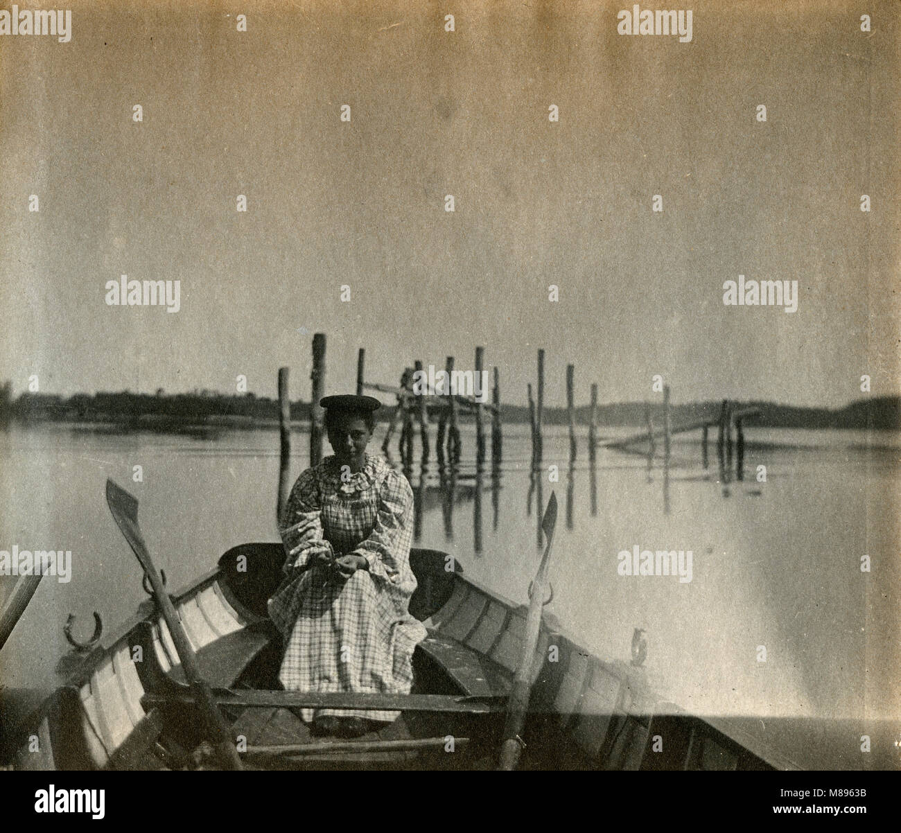 Antique circa 1905 fotografia, donna in canotto con palificazioni dietro di lei nel fiume Sasanoa. La posizione è in o vicino a Riggsville (ora Robinhood), Maine in Sagadahoc County, Stati Uniti d'America. Foto Stock