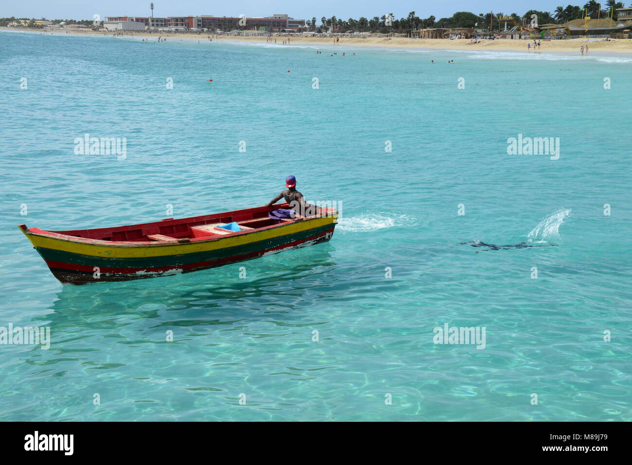 Un maschio si rilassa sulla sua barca mentre un altro maschio nuota vicino, vicino a spiaggia di Santa Maria, sull isola di Sal, in Capo Verde (un ex colonia portoghese). Foto Stock