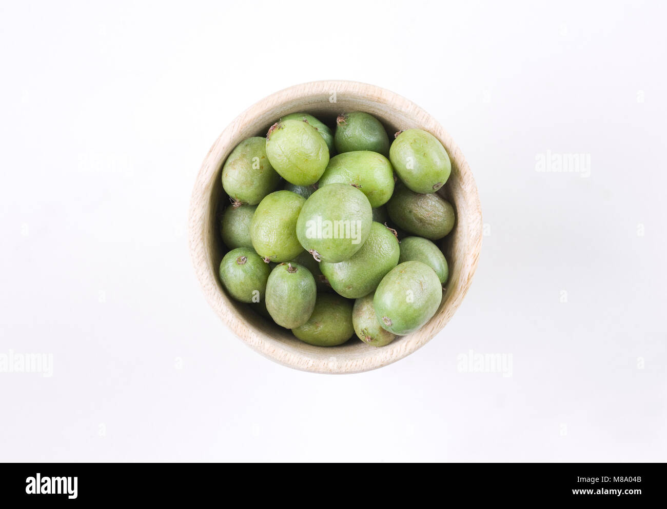Actinidia arguta. Bacche di Kiwi in una ciotola di legno. Foto Stock