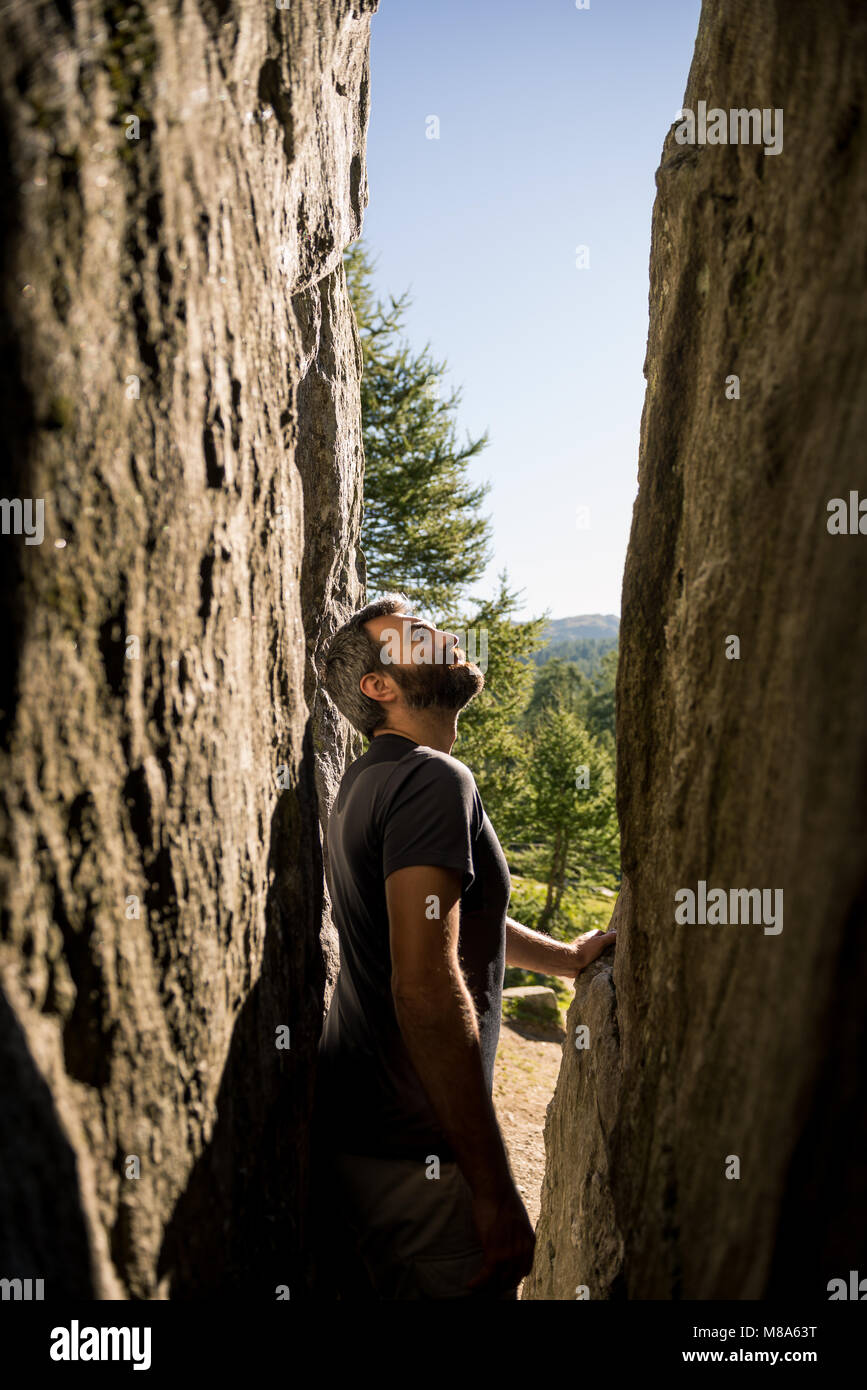 Giovane adulto uomo Attiva esplorazione di parete di roccia nella soleggiata giornata estiva in montagna all'aperto. Foto Stock