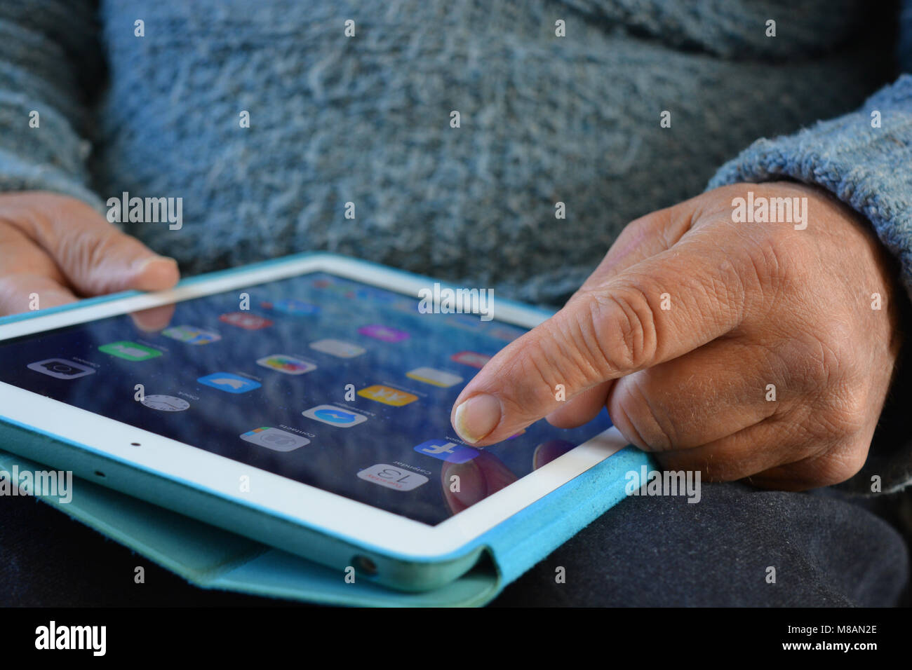 Senior uomo con un iPad, il dito sullo schermo a sfioramento sull'icona di Facebook Foto Stock