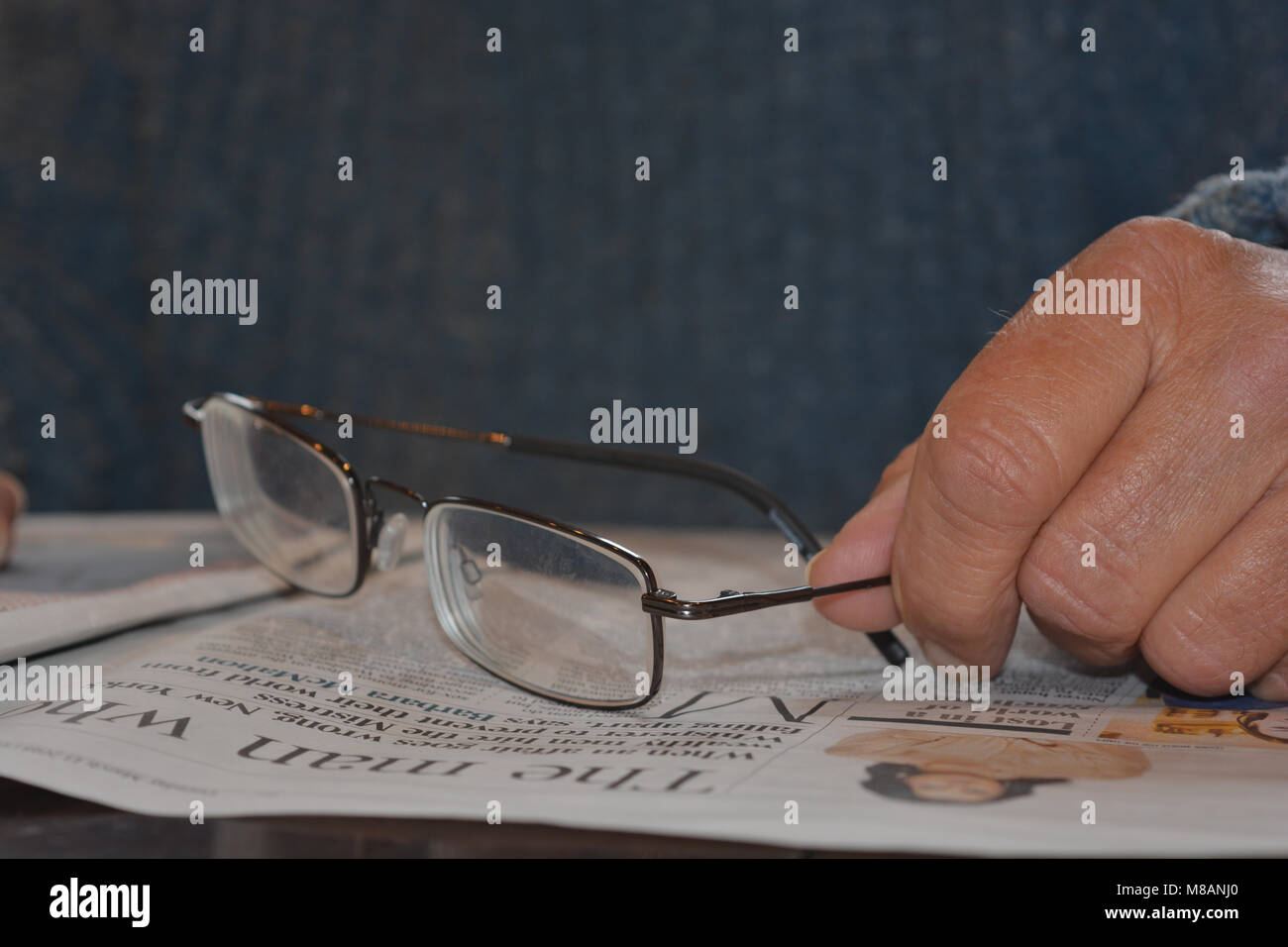 Senior uomo leggendo un giornale, bicchieri in mano Foto Stock
