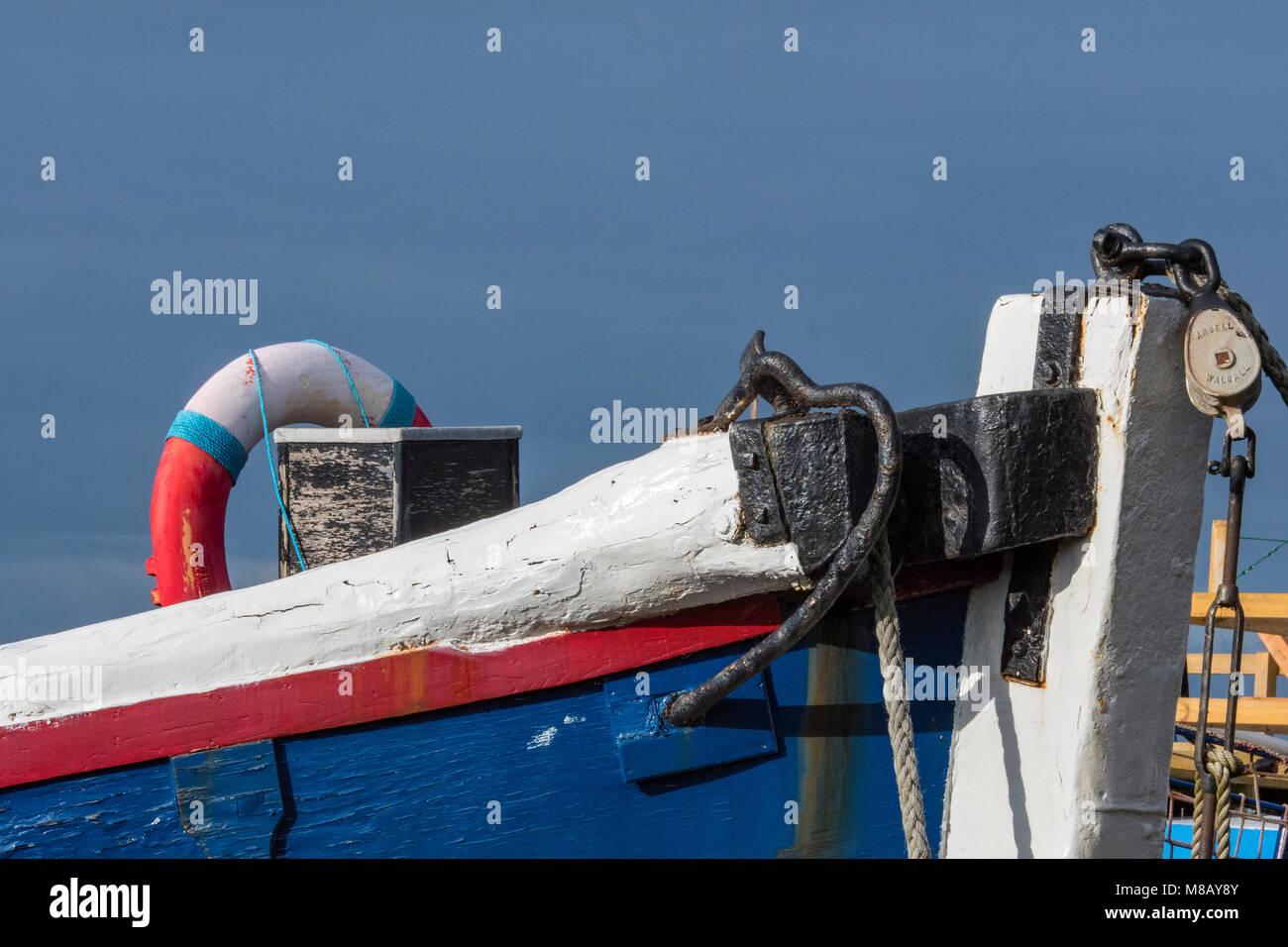 Le centine o la parte anteriore di una vecchia imbarcazione in legno in rosso bianco e blu patriottica di vernici colorate contro il cielo blu con funi e pulegge. costiere nautico Foto Stock