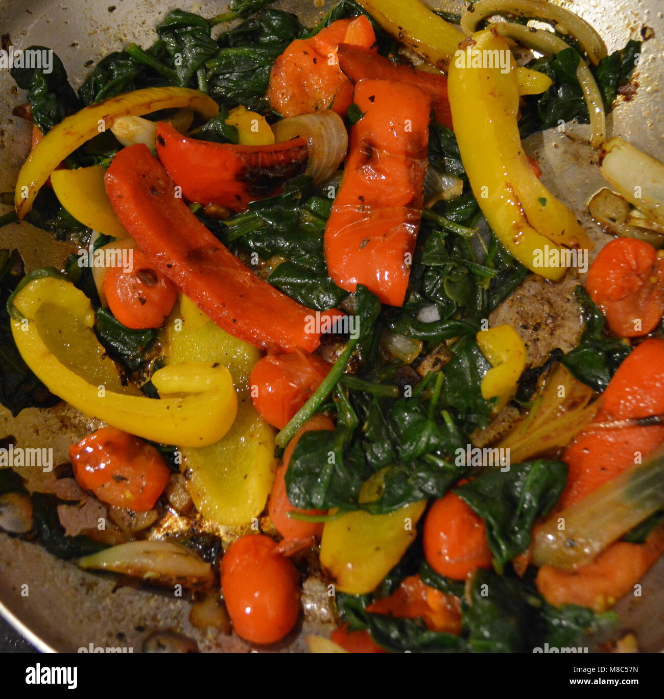 Verdure miste frittura in un piatto di pesata in acciaio inox con fondo di rame - vegetali includono gli spinaci, il peperone rosso, il peperone giallo, e cipolla Foto Stock