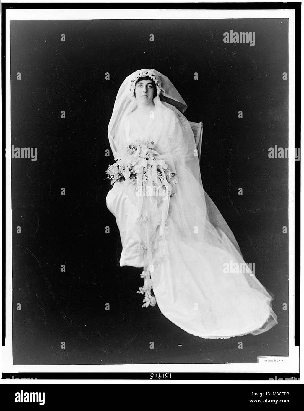 Questo ritratto a figura intera cattura Eleanor Randolph Wilson, figlia del presidente degli Stati Uniti Woodrow Wilson, nel suo abito da sposa che regge un bouquet, simboleggiando un momento significativo nella storia americana dei primi anni del XX secolo. Foto Stock