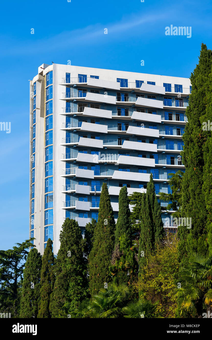 SOCHI, Russia - 18 novembre 2017: cellule residenziale dell'ostello edificio. Moderna architettura minimalista con un sacco di balconi dell'edificio. Alberi ad alto fusto prima della costruzione Foto Stock