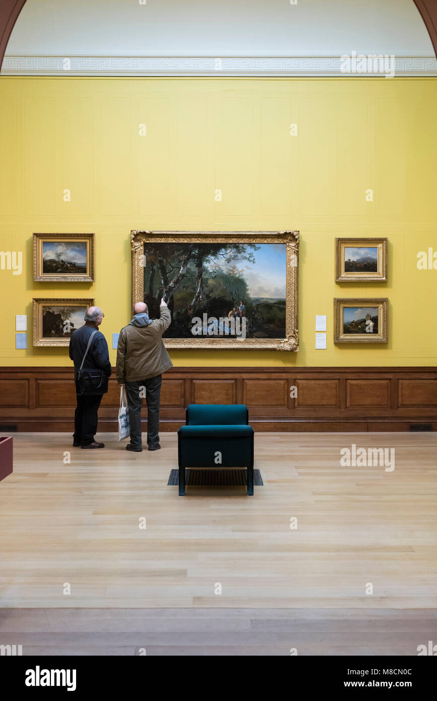 Londra. In Inghilterra. Regno Unito. Dulwich Picture Gallery, visitatori guardando Adam Pynackers' 'Paesaggio con atleti e gioco", ca. 1661-65. Foto Stock