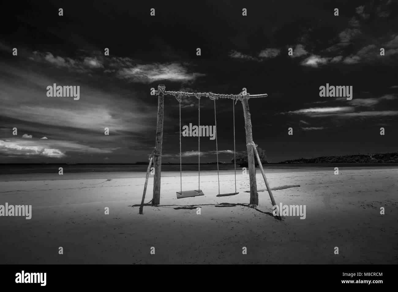 Fotografia di un swing in legno sulla spiaggia in bianco e nero Foto Stock