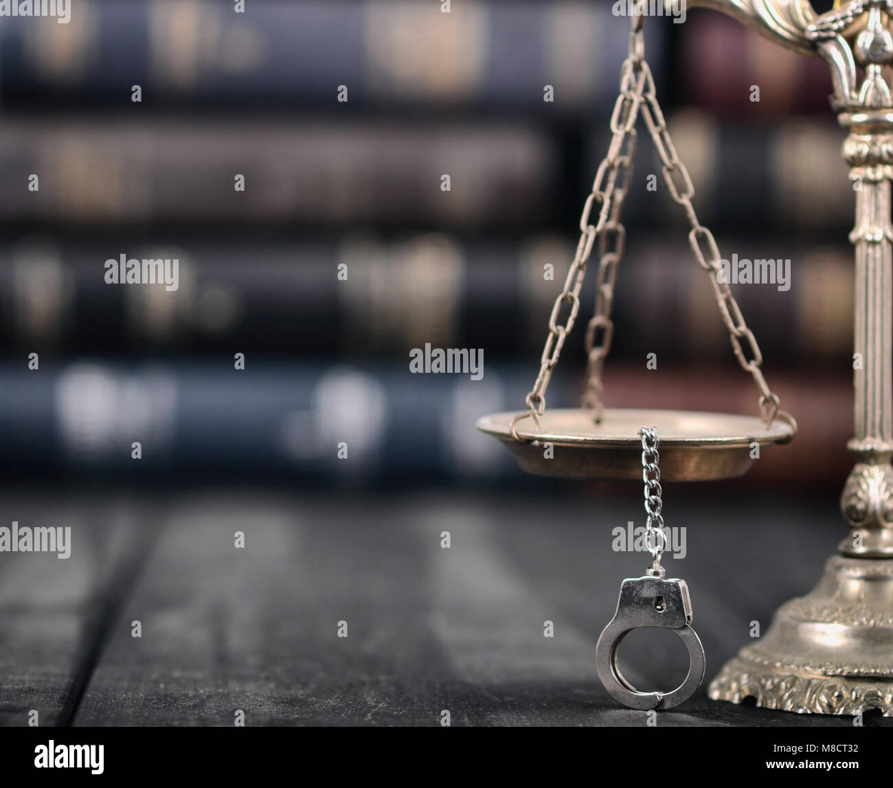 Il diritto e la giustizia, il concetto di legalità, bilancia della giustizia e manette su un nero lo sfondo di legno. Foto Stock