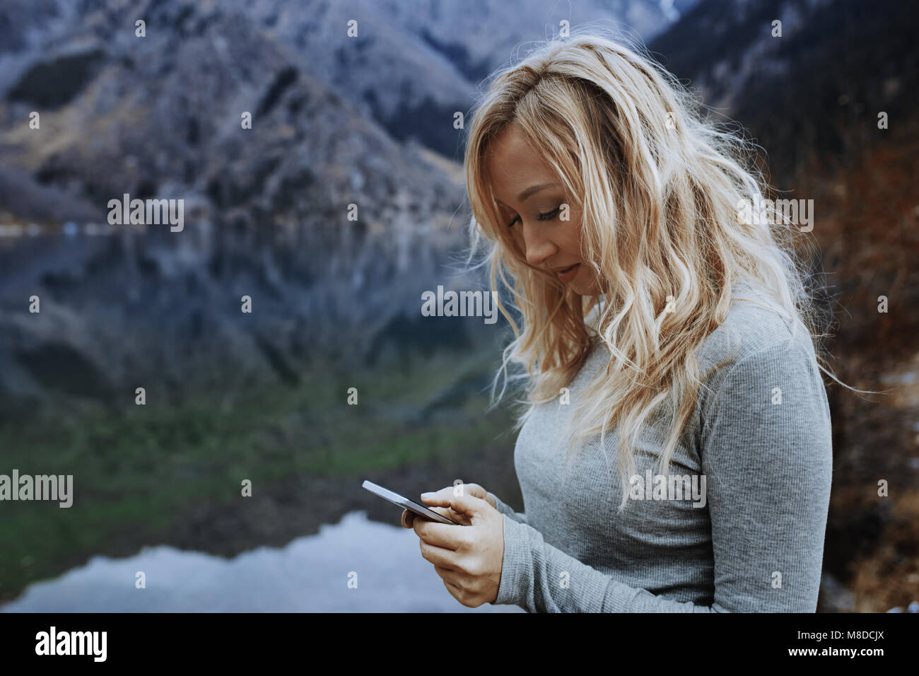 Donna che utilizza smartphone a lago Foto Stock