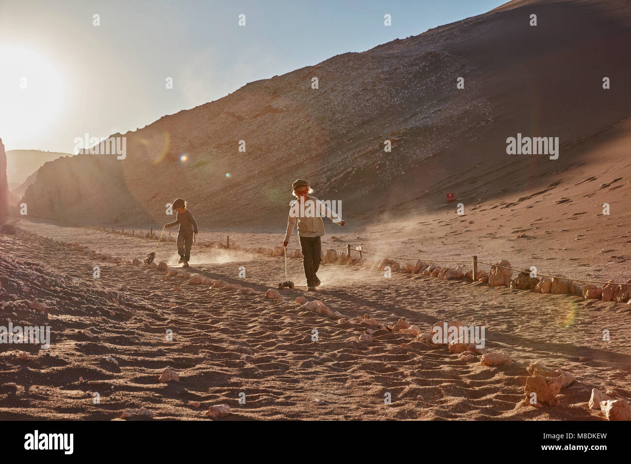 Ragazzo e suo fratello tirando i camion giocattolo lungo il percorso del deserto di Atacama, Cile Foto Stock