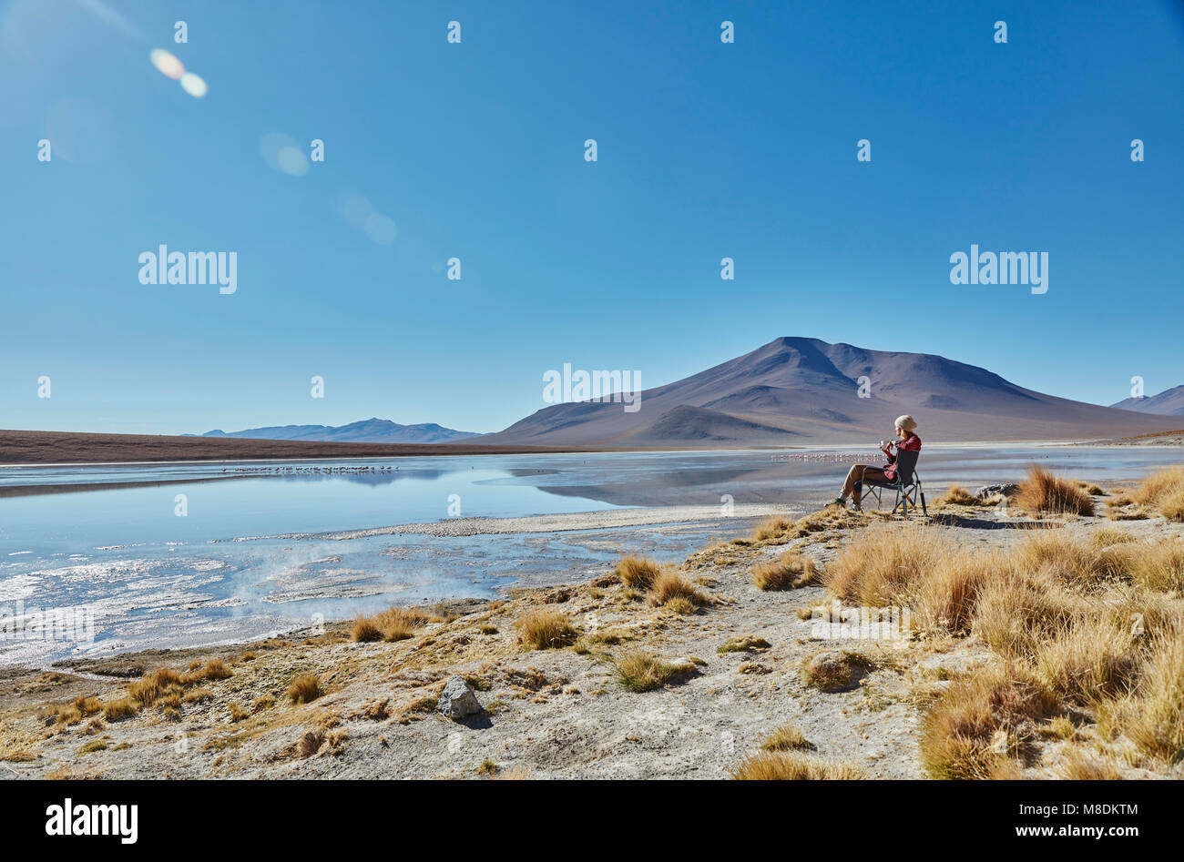Donna seduta in campeggio sedia, guardando a vista, Salar de Chalviri, Chalviri, Oruro, Bolivia, Sud America Foto Stock