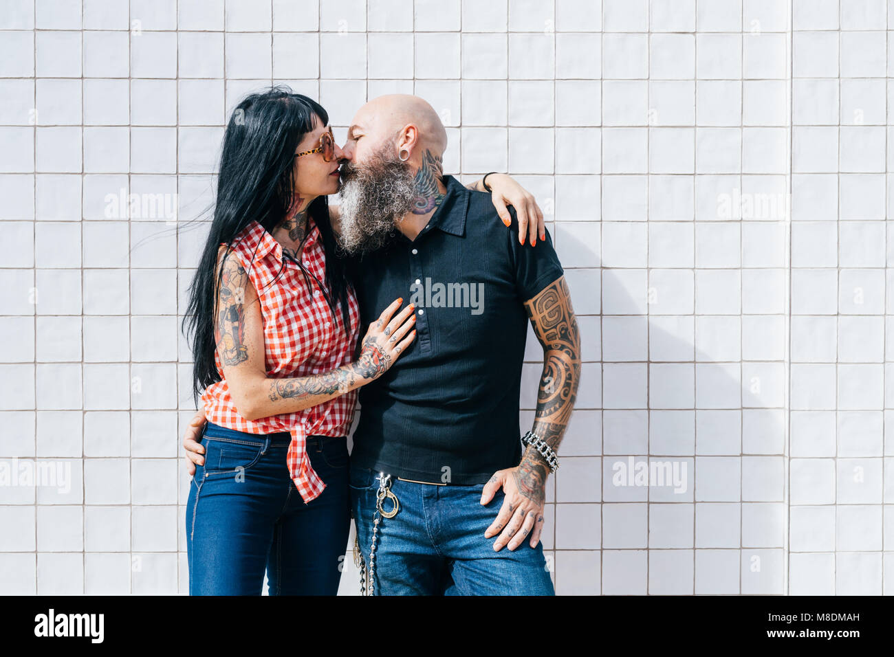 Coppia hipster giovane kissing davanti al muro bianco Foto Stock