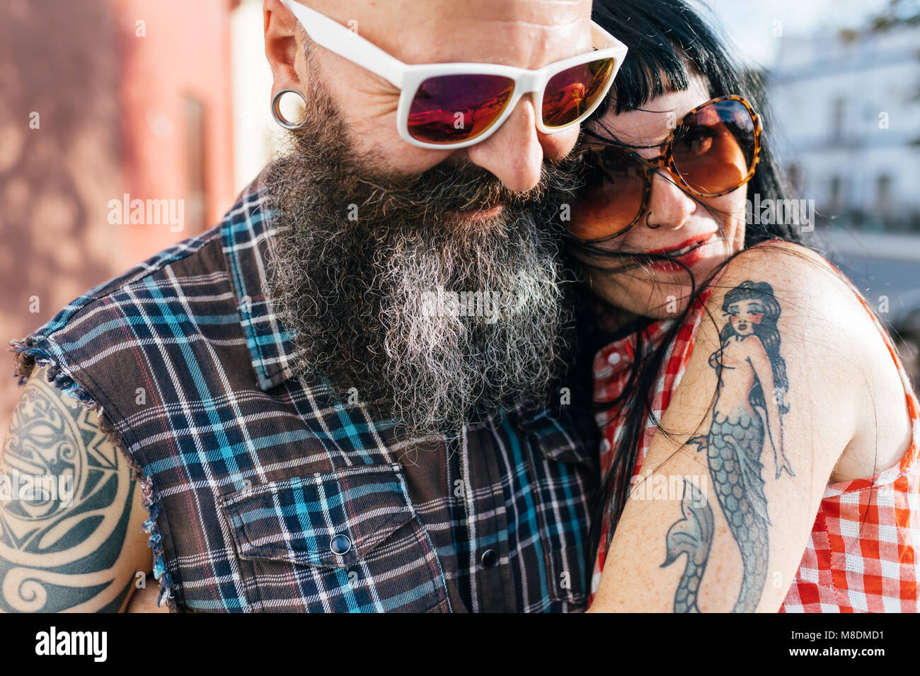 Coppia tatuato hipster giovane abbracciando sul marciapiede, close up Foto Stock