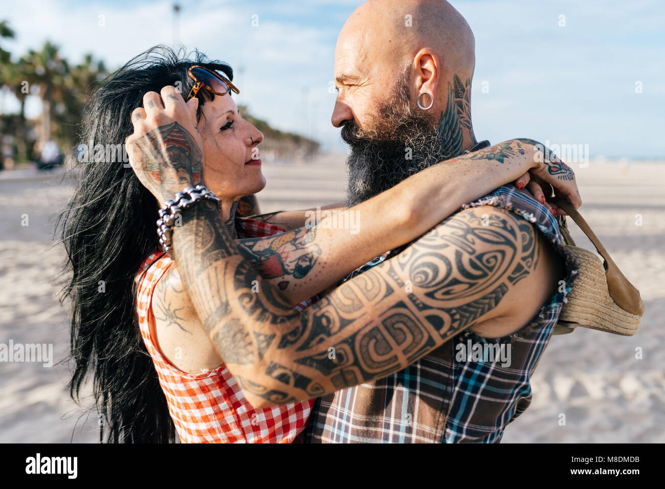 Coppia tatuato hipster giovane faccia a faccia sulla spiaggia, Valencia, Spagna Foto Stock