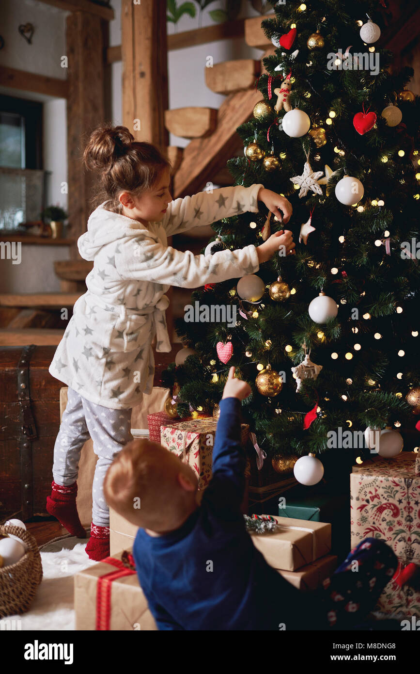 Giovane ragazza e ragazzo decorare albero di Natale Foto Stock