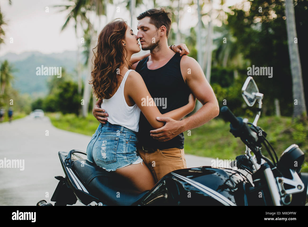 Romantico coppia giovane abbracciando in motocicletta sulla strada rurale, Krabi, Thailandia Foto Stock