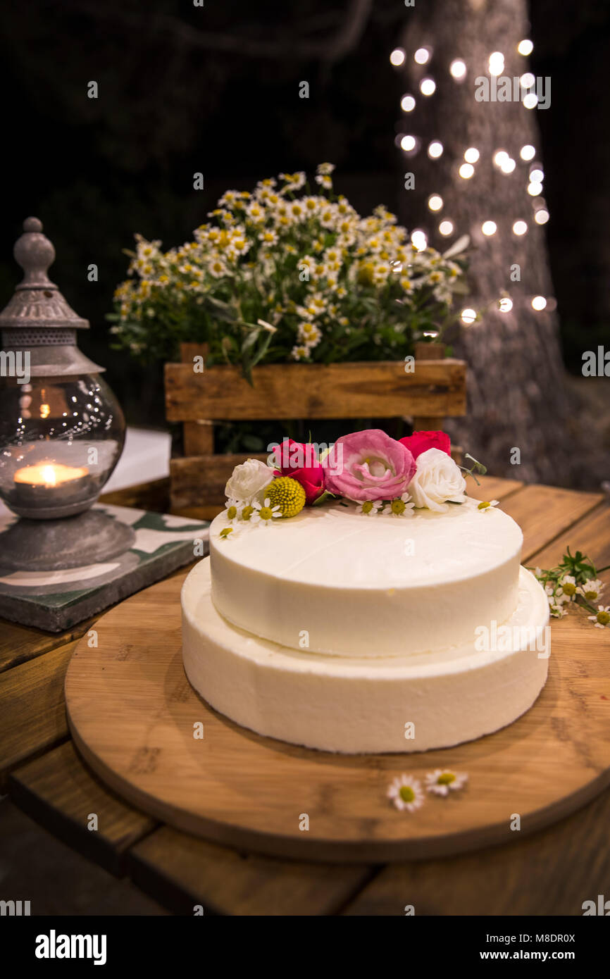 Torta nuziale decorata con fiori su tavola di legno Foto Stock